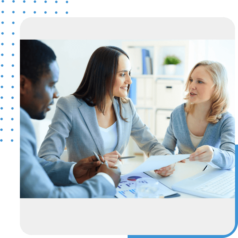 Three people sitting at a table with papers in front of them.