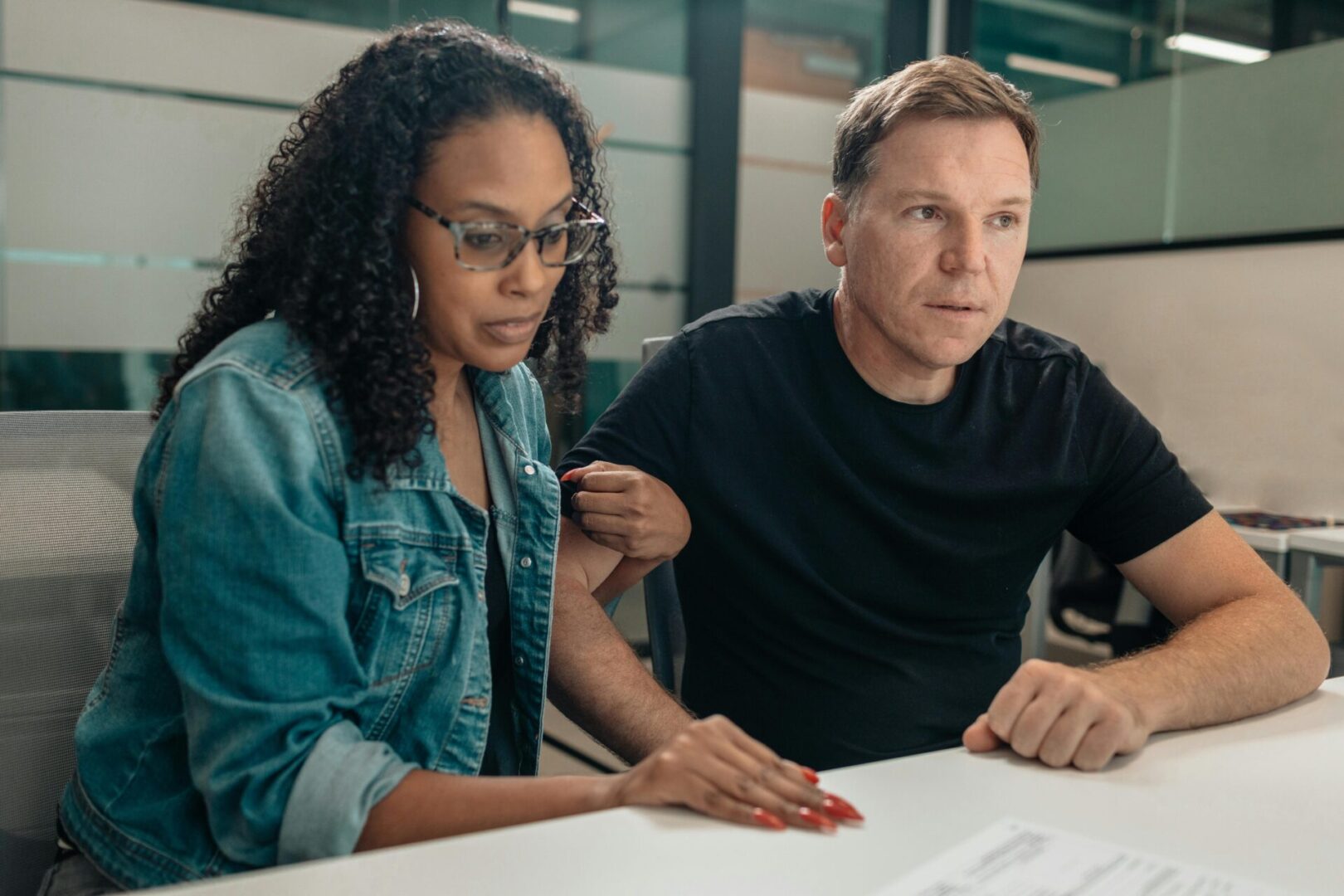 A man and woman sitting at a table looking at something.