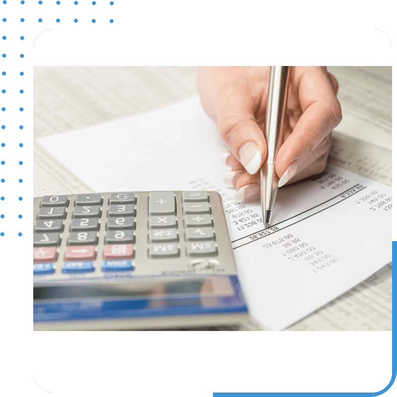 A person writing on paper next to a calculator.